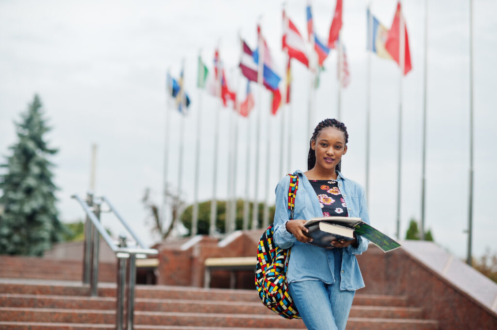 African student female posed with backpack and school items on y