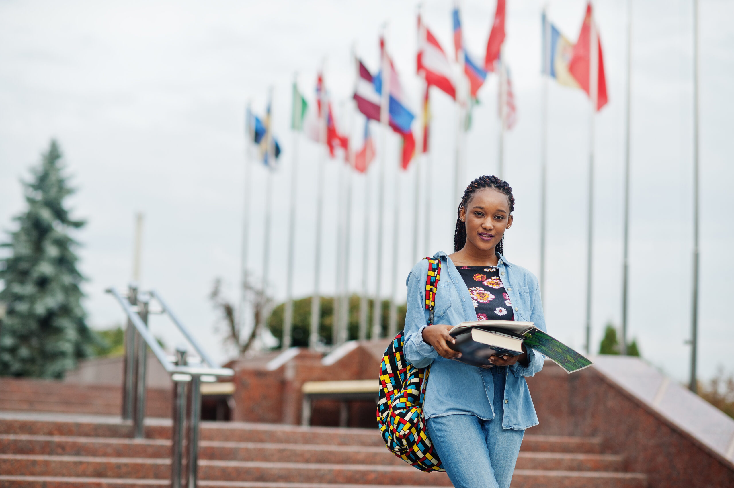 African student female posed with backpack and school items on y